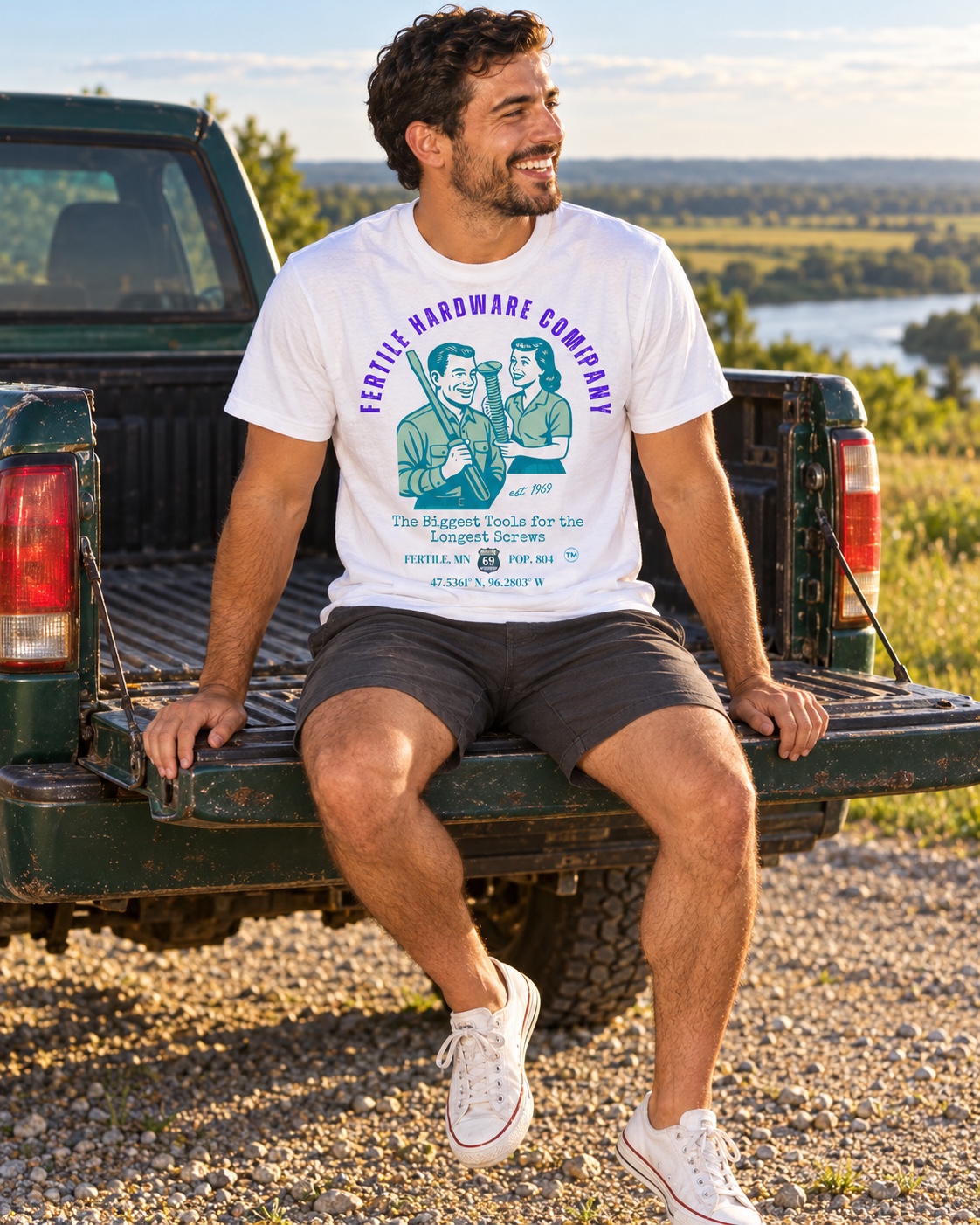 Model wearing the white Fertile Hardware Company tee on a pickup tailgate